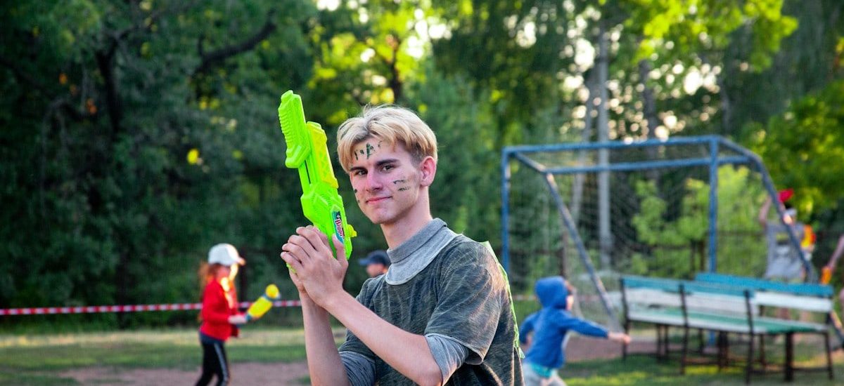 a young man holding a green object in a park