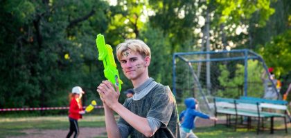 a young man holding a green object in a park