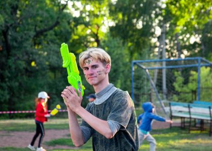 a young man holding a green object in a park